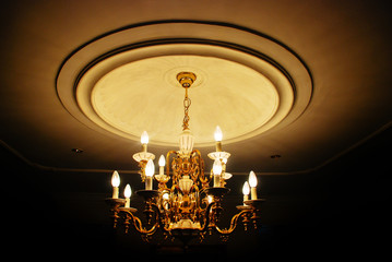 A large chandelier with candle shaped lights in a dark room