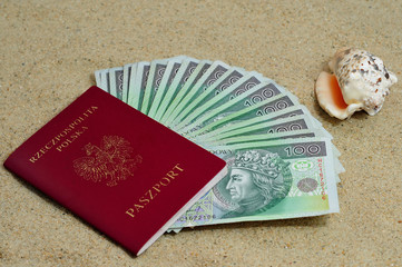 Polish passport with money inside on sand with sea shell