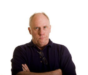 Fototapeta premium An older bald man in a blue shirt with arms crossed