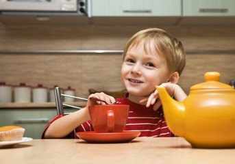 Child drinks tea with cakes