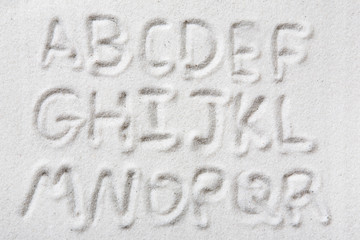 First half of an upper case alphabet written in sand