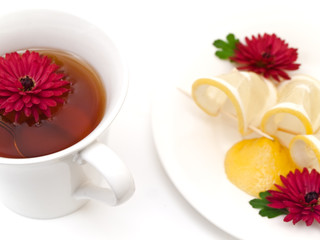 Fototapeta na wymiar cup of tea near the plate with lemon and flowers