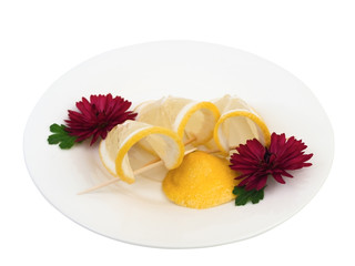 plate with lemon and flowers against the white background
