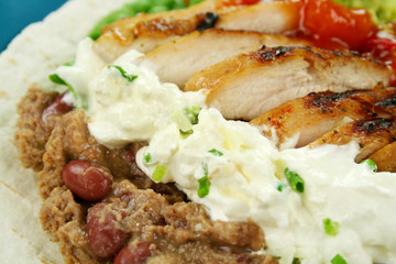Open chicken tortilla with refried beans and sour cream