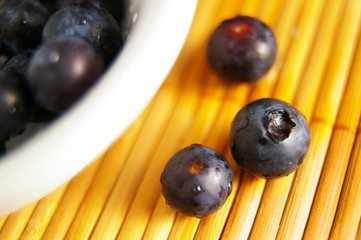closeup of fresh blueberries, and bowl on bamboo