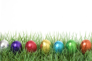 colorful chocolate easter eggs in a row on grass with copy space