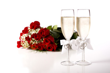 A bouquet of red roses and tow champange flutes