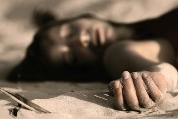 woman playing dead, lying in the sand