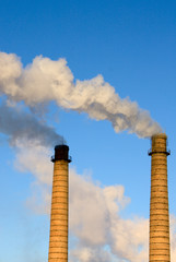 Brick pipes with a smoke on a background of the clear blue sky