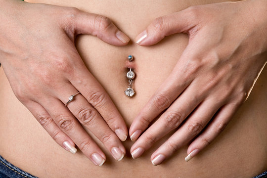 love shape hand sign on a woman piercing tummy