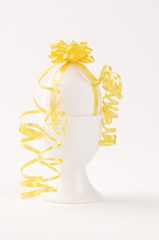 a white egg decorated with a yellow ribbon