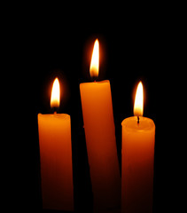 three candles over black background