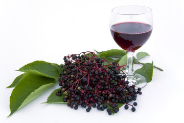 Holunderbeeren und ein Glas mit Holundersaft auf einem weißen Hintergrund