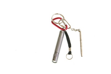Keychain gadgets. Miniature flashlight, clips, eyeglass tools and keyrings on white