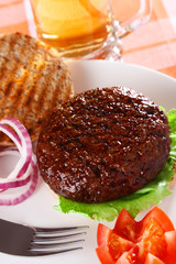 classic opened beef burger with beer on background, shallow DOF