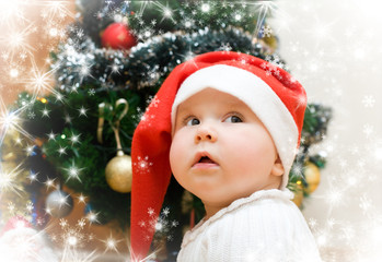 Little girl in red Santa hat wishing under christmas tree