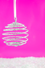 hanging sparkly swirly  christmas ball with reflection on pink