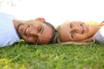 Obraz na płótnie Canvas beauty young caucasian couple laying on grass outdoor