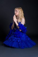 Beautiful girl in a dark blue dress prays