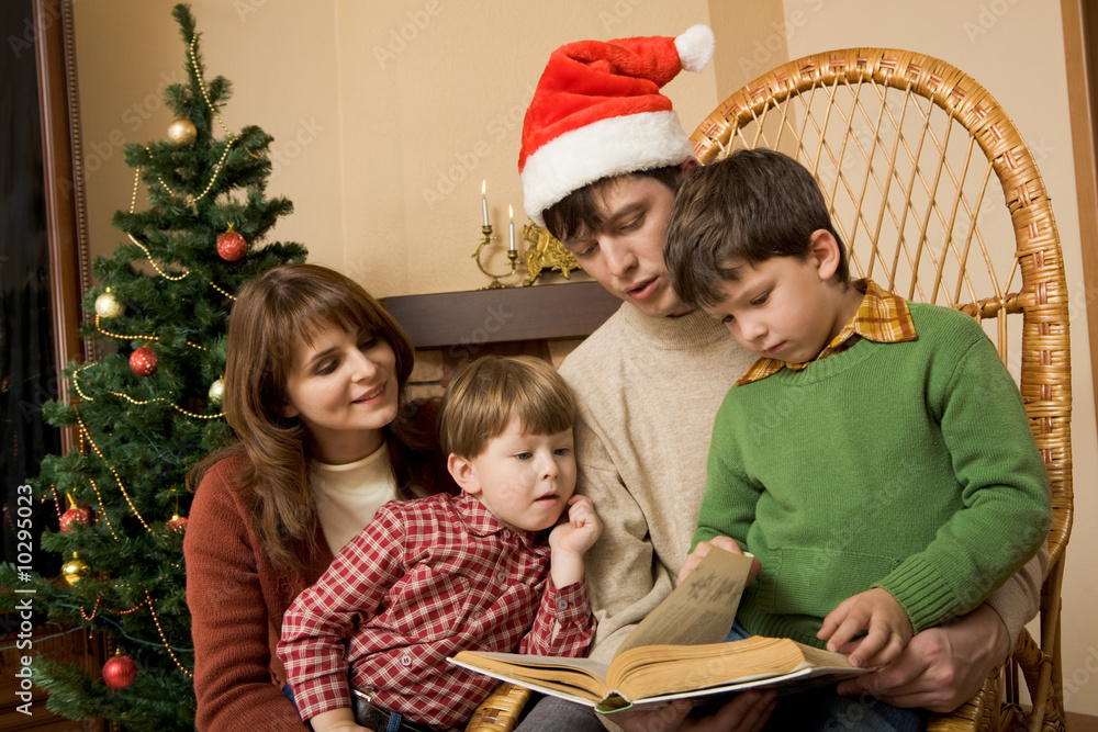 Wall mural Portrait of friendly family looking into interesting book