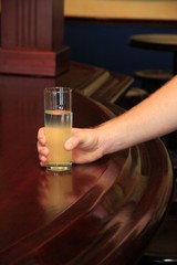 Hand holding a drink on a wooden pub or bar counter