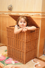 Girl in basket for linen in bathroom