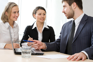 Image of business conversation of three businesspeople