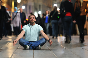 young man meditating yoga in lotus position at street - obrazy, fototapety, plakaty