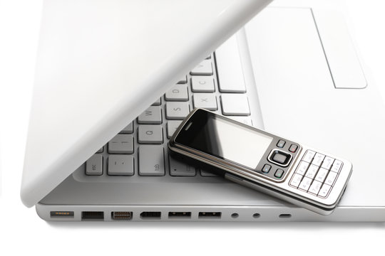 White laptop with silver-black phone on it. Hikey scene.