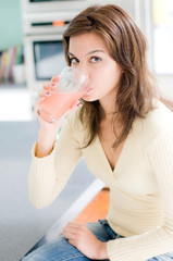 A beautiful young woman drinking grapefruit juice