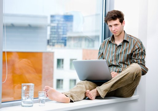 Businessman sitting in office window and working on laptop