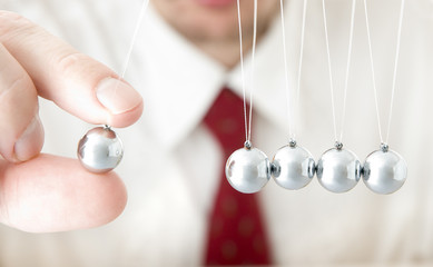 Businessman hand holding a pendulum ball