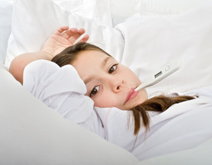 young girl lying in bed with a thermometer