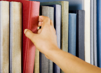 Image of a hand selecting a red book from a bookshelf