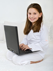 young girl with a laptop computer on the bed