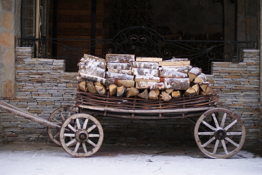 Old cart with wood with stone wall at background