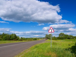 Road in countryside with dangerous turn left sign