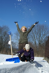 mother and her daughter shoveling and throw up snow