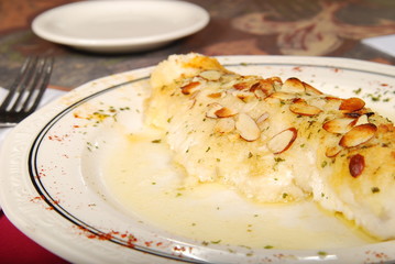 Fish with almonds on a white plate on a table