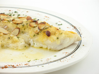 Fish with almonds on a white plate on a white background