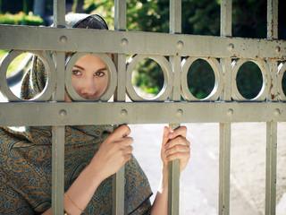 east woman hiding behind the grid looking straight