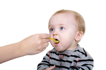 Cute baby being feed rice cereal with a yellow spoon