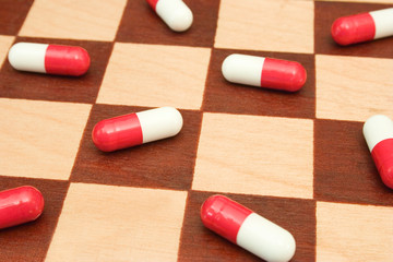 Pills on chessboard, abstract medical background