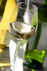 weisswein im glas flaschen unscharf dahinter