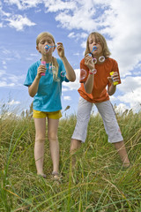 Children blowing bubbles on summer meadow