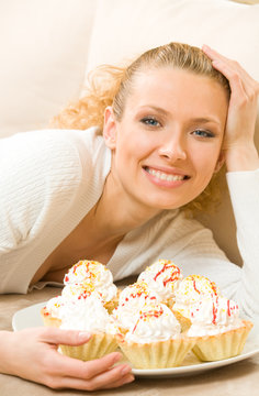 Young happy smiling woman with plate of cakes at home