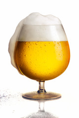 Bowl of beer with drops, foam spilling at the right side