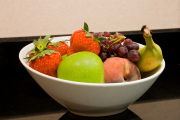 Naklejka na ściany i meble Close up of white fruit bowl with apple, strawberries, banana