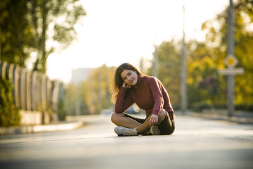 Beautiful smiling girl sitting on the road