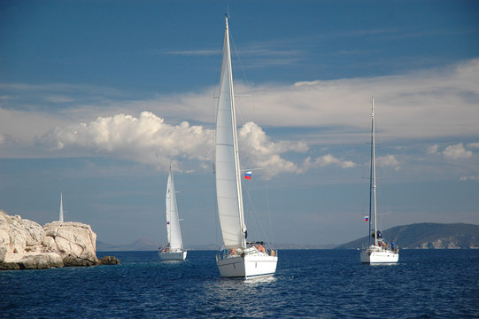 Fototapeta cztery jachty żeglują po morzu prawie po skale